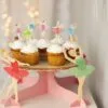 Вкусни капкейци с бели глазури и цветни украси, сервирани на красив тнап за сладки изкушения, подходящ за детско парти или тържество.