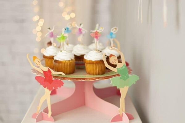 Вкусни капкейци с бели глазури и цветни украси, сервирани на красив тнап за сладки изкушения, подходящ за детско парти или тържество.