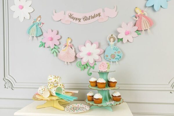 Цветна декорация за детски рожден ден с принцеси и цветя, чудесно украсена маса с торти и кексчета за парти. Подходяща за празненства, организирани от Party Deluxe.