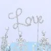 Бляскав фуний за торта с надпис Love, украсен с кристални елементи и перли, идеален за романтични събития и сватби.