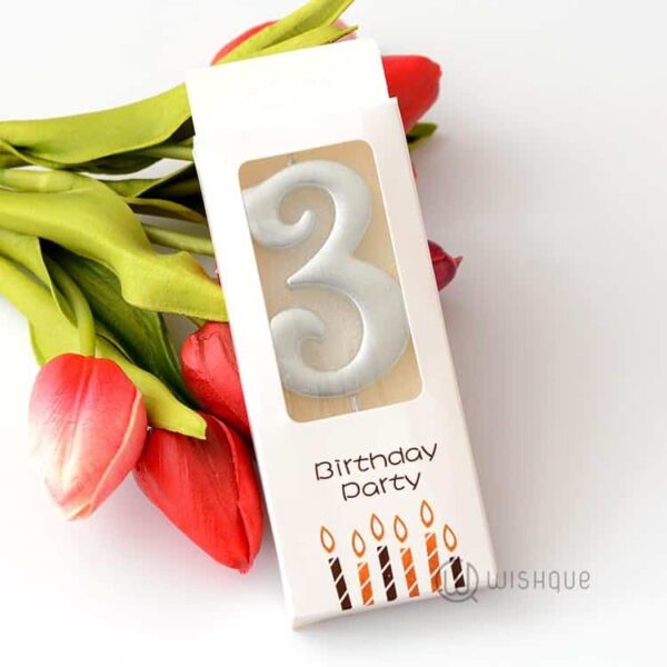 3. Възрастовият свещ за рожден ден с номера 3, подходяща за тържества и празненства, върху бяла кутия с цветни свещи.