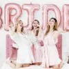 Бронзови балони със надпис "BRIDE" за сватбено парти, момичета на вечеря с разпускане и забавление, празнична атмосфера с розови декорации и цветя, перфектно за бижута и тематични събития.