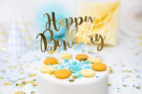 Хубав торт за рожден ден с "Happy Birthday" украсител и макарони, празнична атмосфера, сладки изкушения и конфети, перфектен за парти и специален повод.