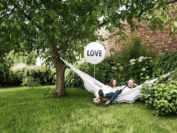 Лозунг за парти на открито с любов, романтична двойка в хамак сред зеленина и цветя, подходяща за организиране на събития и празници, Party Deluxe България.