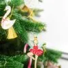 Цветна коледна елхова украса с празнични украшения и висящи ornaments за рожденка с танцьорка и елхови декорации, подходяща за празнична обстановка и парти.