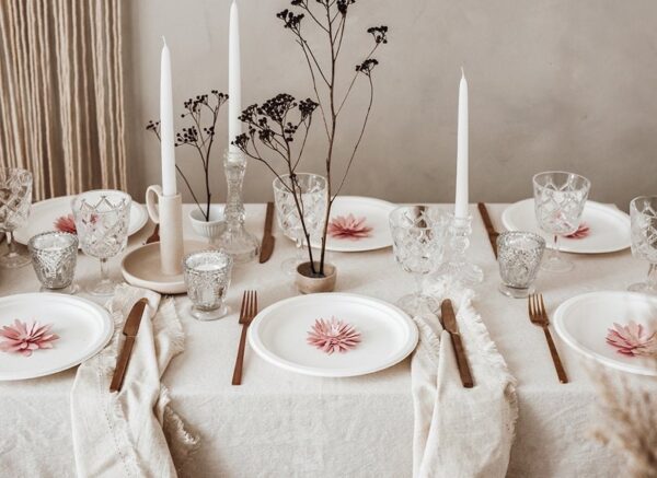 Изискана празнична маса с розови цветя, свещи и кристални чаши за специални събития, създаваща уютна и елегантна атмосфера за празнични празници и торжества.