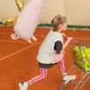 Бебе с балон в форма на прасенце, играеща с пазарска количка с играчки, на интериорно събитие или парти, фотография от Party Deluxe.