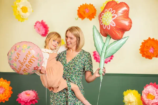 Възрастна жена и млада девойка с цветни балони, празнична обстановка с хартиени цветя на заден план, подходящи за парти и семейни събития, идеи за украса и забавление на гости.