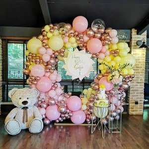 Розова и златист балонна декорация за рожден ден с голямо поздравително табло, плюшен мечок и цветна торта, идеална за празненство, организирана от Party Deluxe.