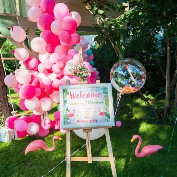 Фламинго парти на трева с розови балони и табела Welcome на статив