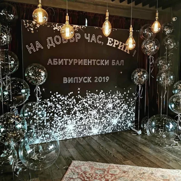 Фотозона за абитуриентски бал с черно пано, прозрачни балони с конфети и ретро крушки